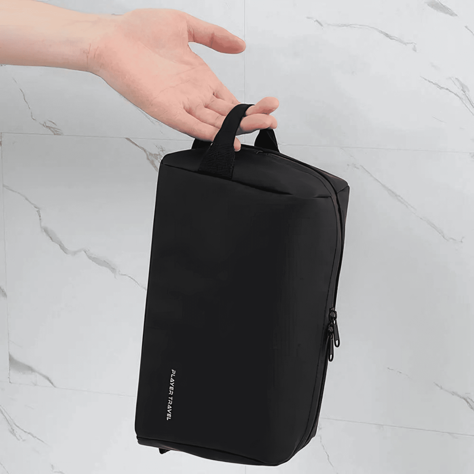 Trousse de toilette homme imperméable noire Player Travel tenue à la main, format compact et pratique pour le voyage.