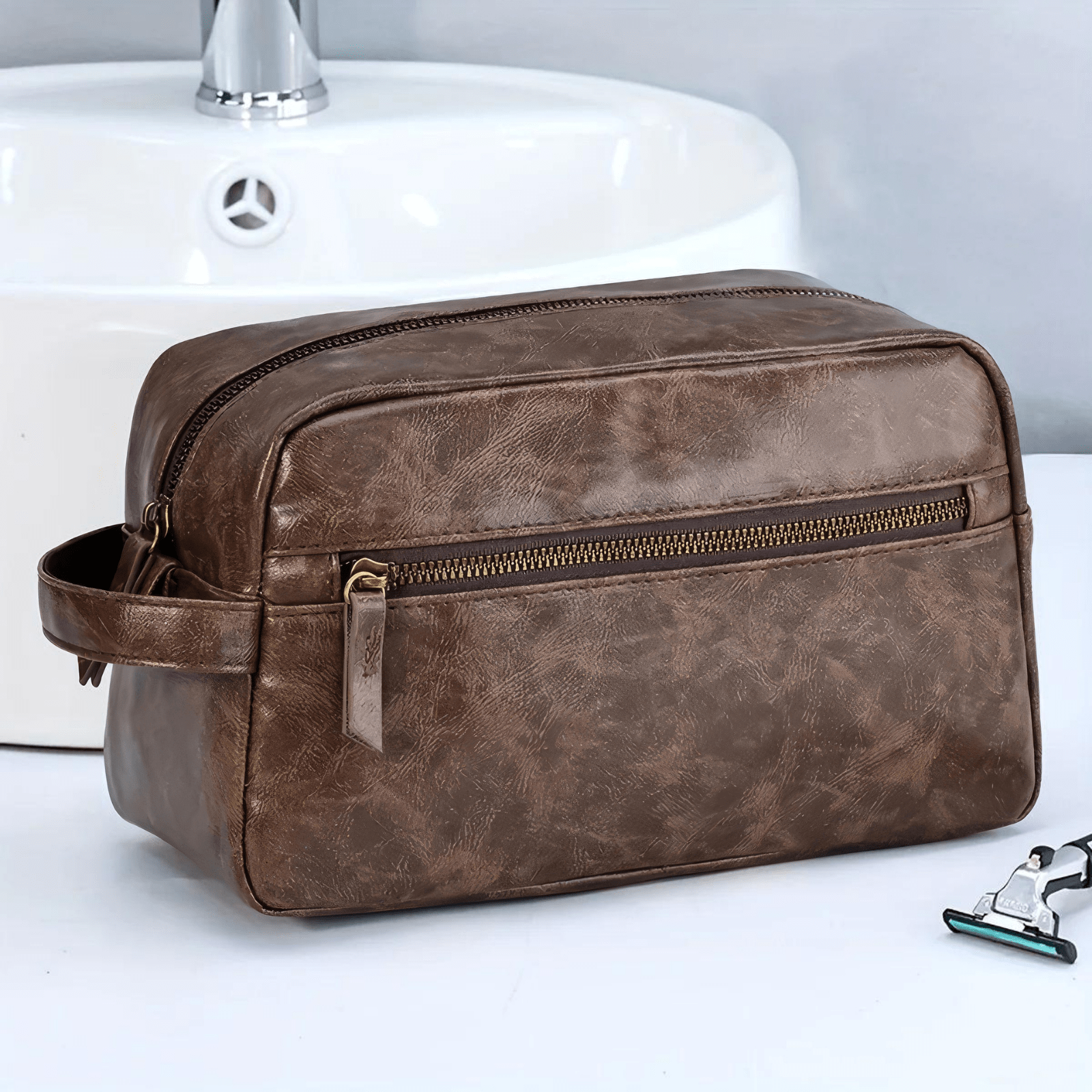 Trousse de toilette homme simili cuir marron foncé pour voyage posée près du lavabo