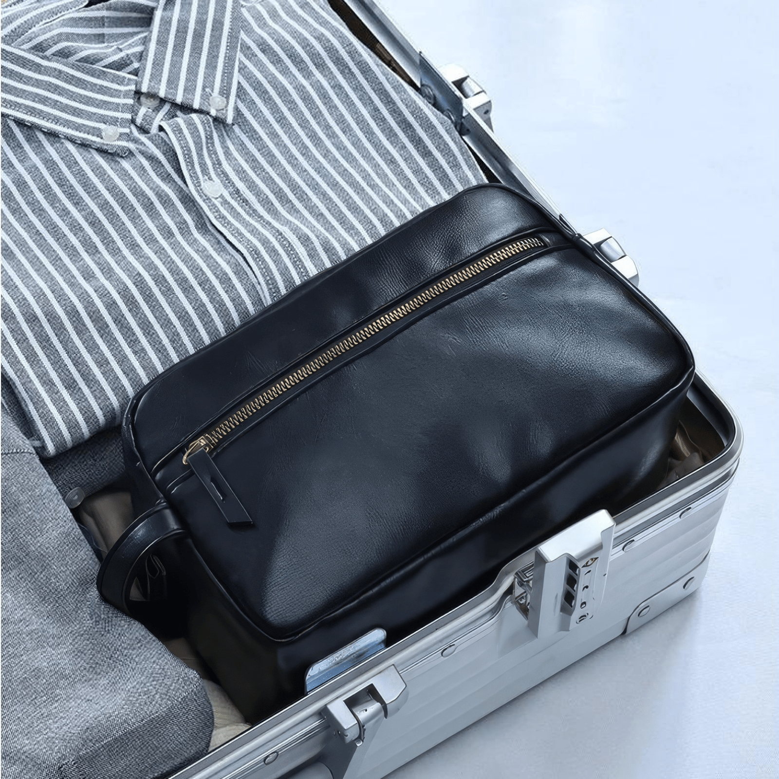 Trousse de toilette homme simili cuir noir pour voyage rangée dans une valise avec vêtements