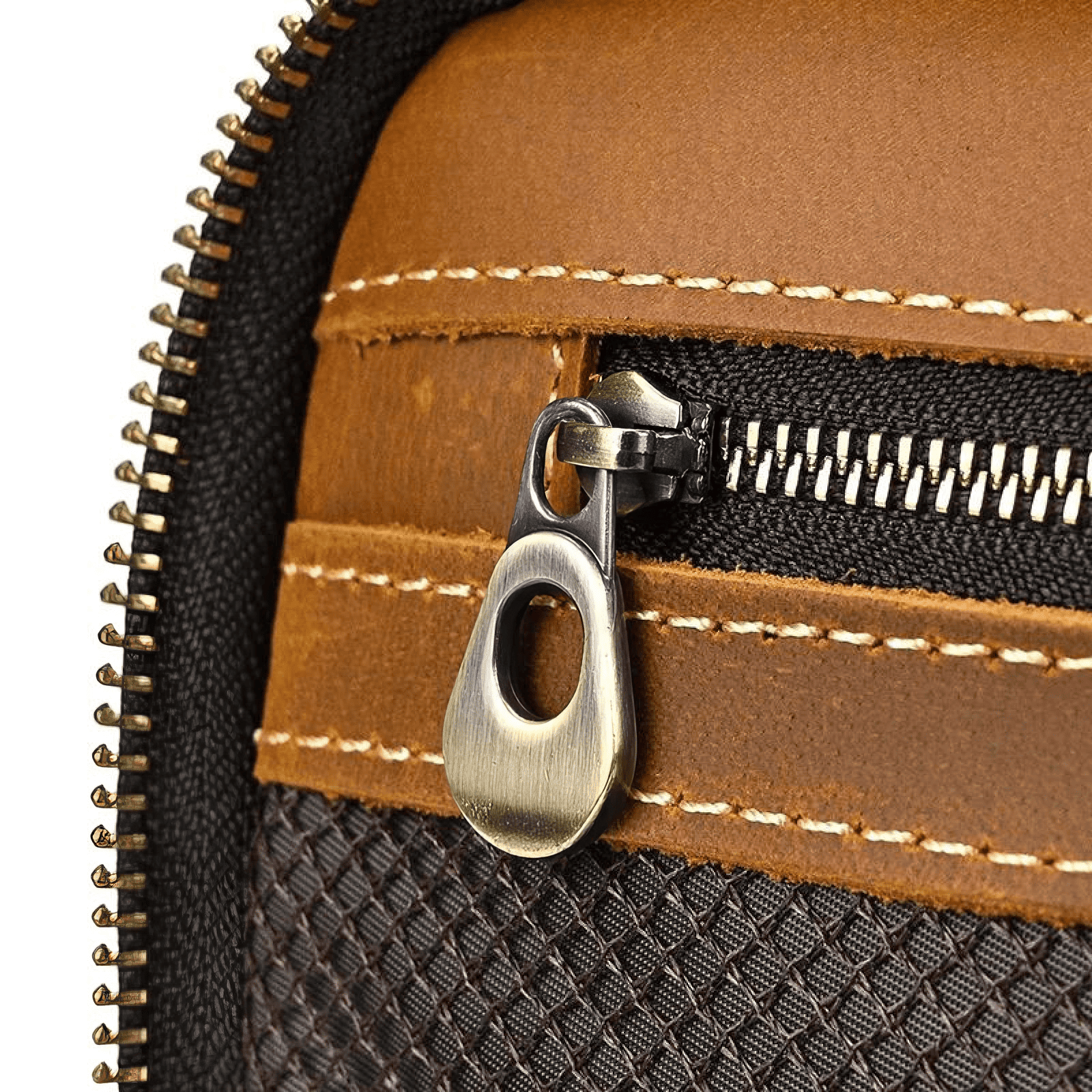 Gros plan sur la fermeture métallique et la texture en cuir de la trousse de toilette homme cuir luxe marron clair, coutures contrastées visibles.