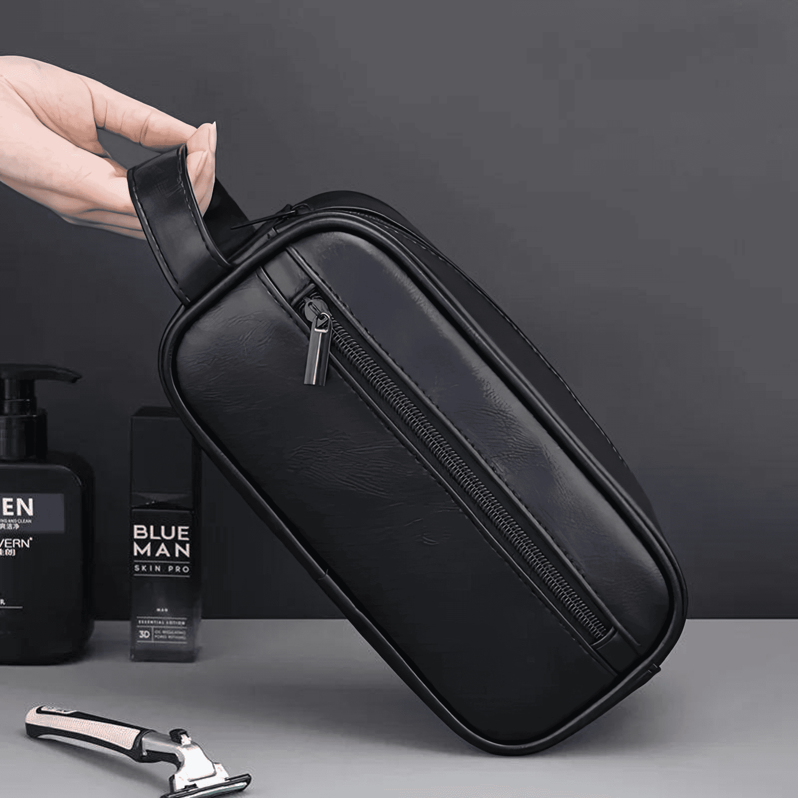 Trousse de toilette homme en simili cuir noir avec poignée latérale, design élégant et résistant à l’eau.