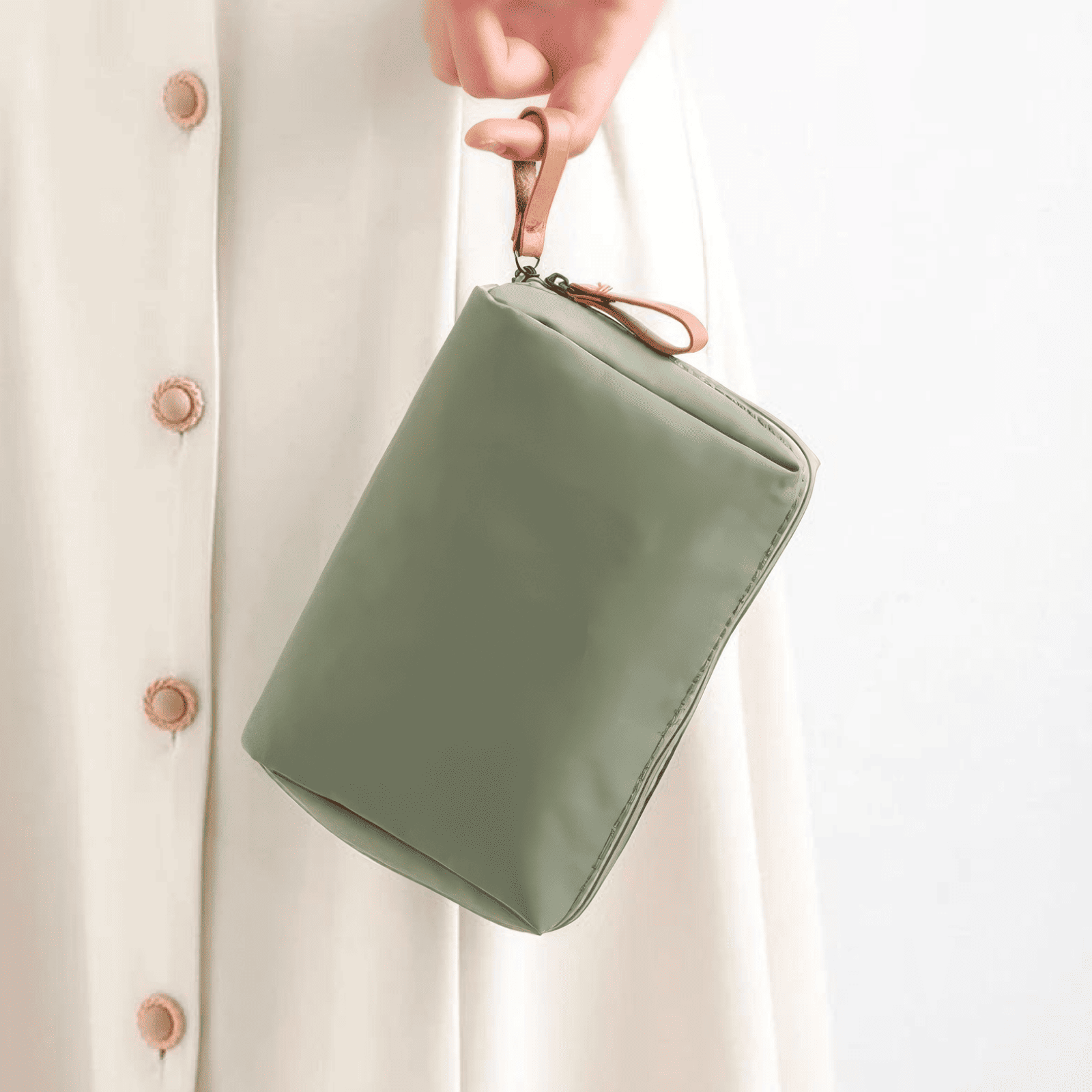 Trousse de toilette femme plate verte tenue à la main avec poignée en cuir marron